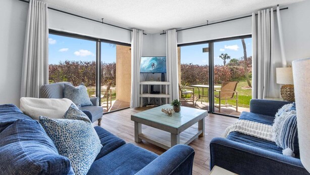 A modern living room with a TV, sofas, and a coffee table. - Beachfront Walkout – Ground-Floor Oceanfront Retreat w/ Private Sand Access & Heated Pool (Cape Canaveral)