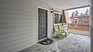 A porch with a gray door, a window with a red frame, and two green Adirondack chairs. - Walk to Lifts: Main Street Breck Condo w/ Mtn View (Breckenridge)