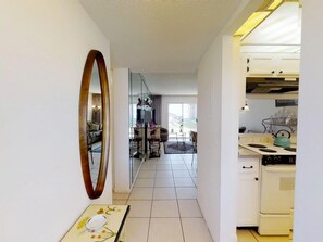Eine moderne Küche mit weißen Schränken und einem türkisfarbenen Wasserkocher. Im Hintergrund ist ein Essbereich mit Tisch und Stühlen zu sehen.
