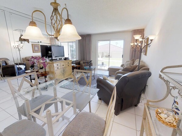Ein Wohnzimmer mit einem Glastisch, zwei Sofas, einem Fernseher und dekorativen Accessoires.