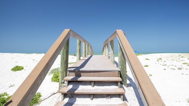 A wooden boardwalk leading to a beach with clear skies. - Beachfront on Pass-A-Grille Beach with Pool! Walking Distance to Great Restaurants and Shops. (St. Pete Beach)