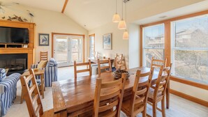 A spacious dining area with a wooden table and chairs, a fireplace, and a large window with blinds. - Duck Haven - Tuckahoe, Easy Walk to Ocean, Pool, Hot Tub, Discounts! (Duck)