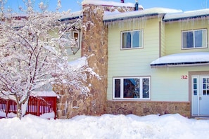 A two-story building with a stone facade and a number '32' on the door. - Remodeled TH Near Resort-Steps to Free Mtn/Town Bus Stop+ HotTub-W/D in Unit-Gas Fireplace-Mtn View (Steamboat Springs)