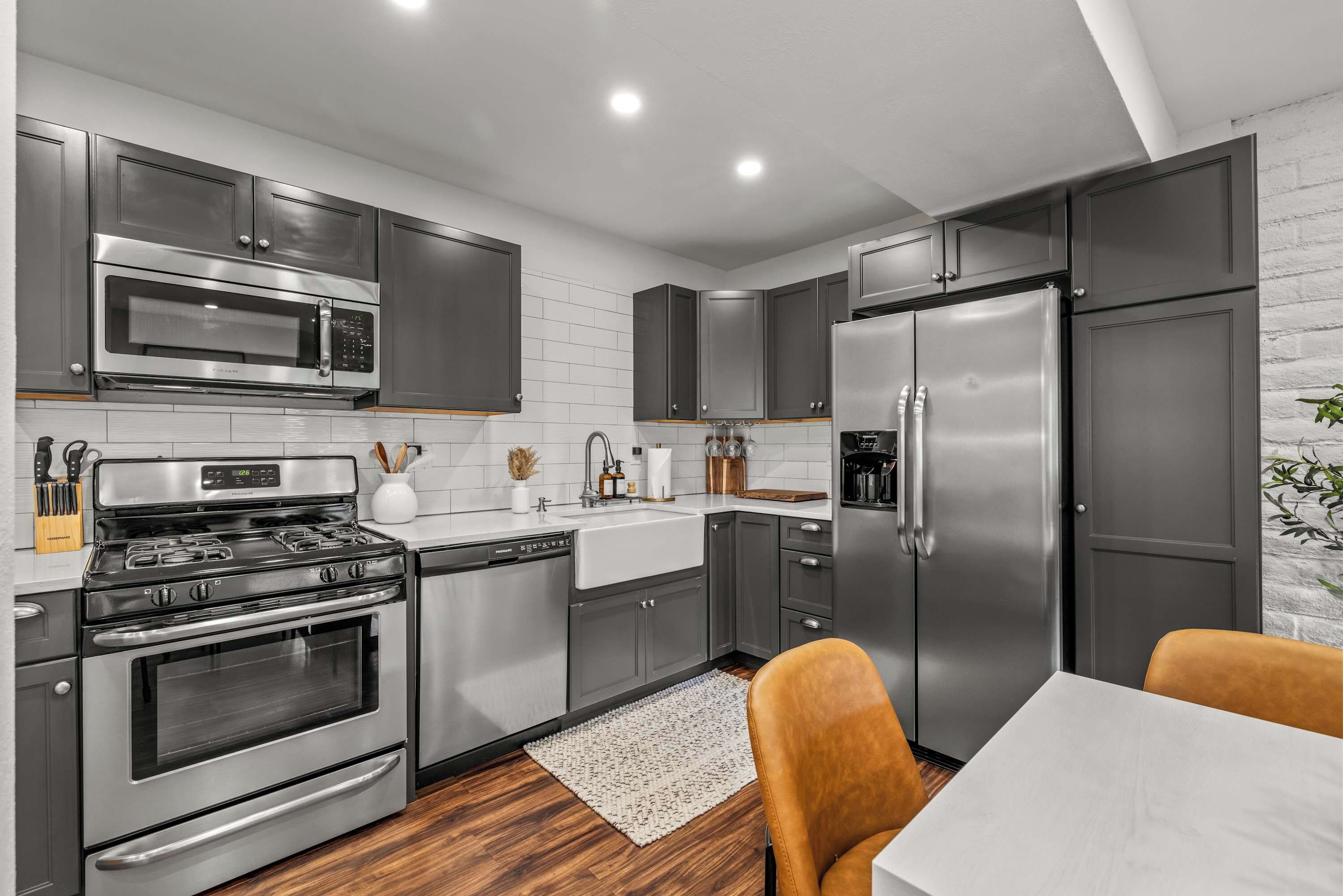 A modern kitchen with stainless steel appliances, grey cabinetry, and a white tiled backsplash.