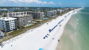 A beachfront hotel with multiple floors, a pool, and beach umbrellas. - SL 101: Sugary Sands - Cute and Cozy with Beautiful Upgrades!! (Fort Walton Beach)