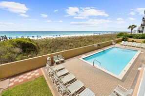 Ein Poolbereich mit Liegestühlen, einem Pool und Blick auf den Strand.