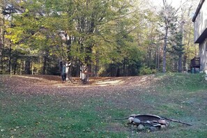 Surrounded by tall trees, this serene outdoor space features a well-maintained lawn and a garden area with a shed in the background.