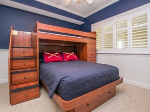 Un letto a castello con struttura in legno, copriletto blu scuro e cuscini rossi.