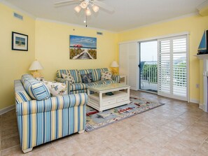 A living room with a striped sofa, a coffee table, and a view of a balcony.