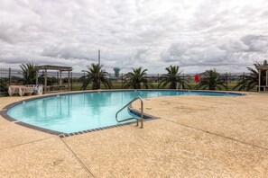 A swimming pool with a metal ladder, surrounded by a fence and palm trees. - < 1 Mi to Beach! Waterfront Galveston Bay Retreat (Galveston)