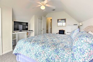 A bedroom with a large bed, a ceiling fan, a TV, and a desk with books. - < 1 Mi to Beach! Waterfront Galveston Bay Retreat (Galveston)