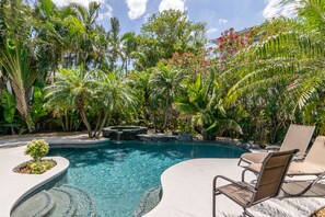 A swimming pool surrounded by lush tropical plants and palm trees.