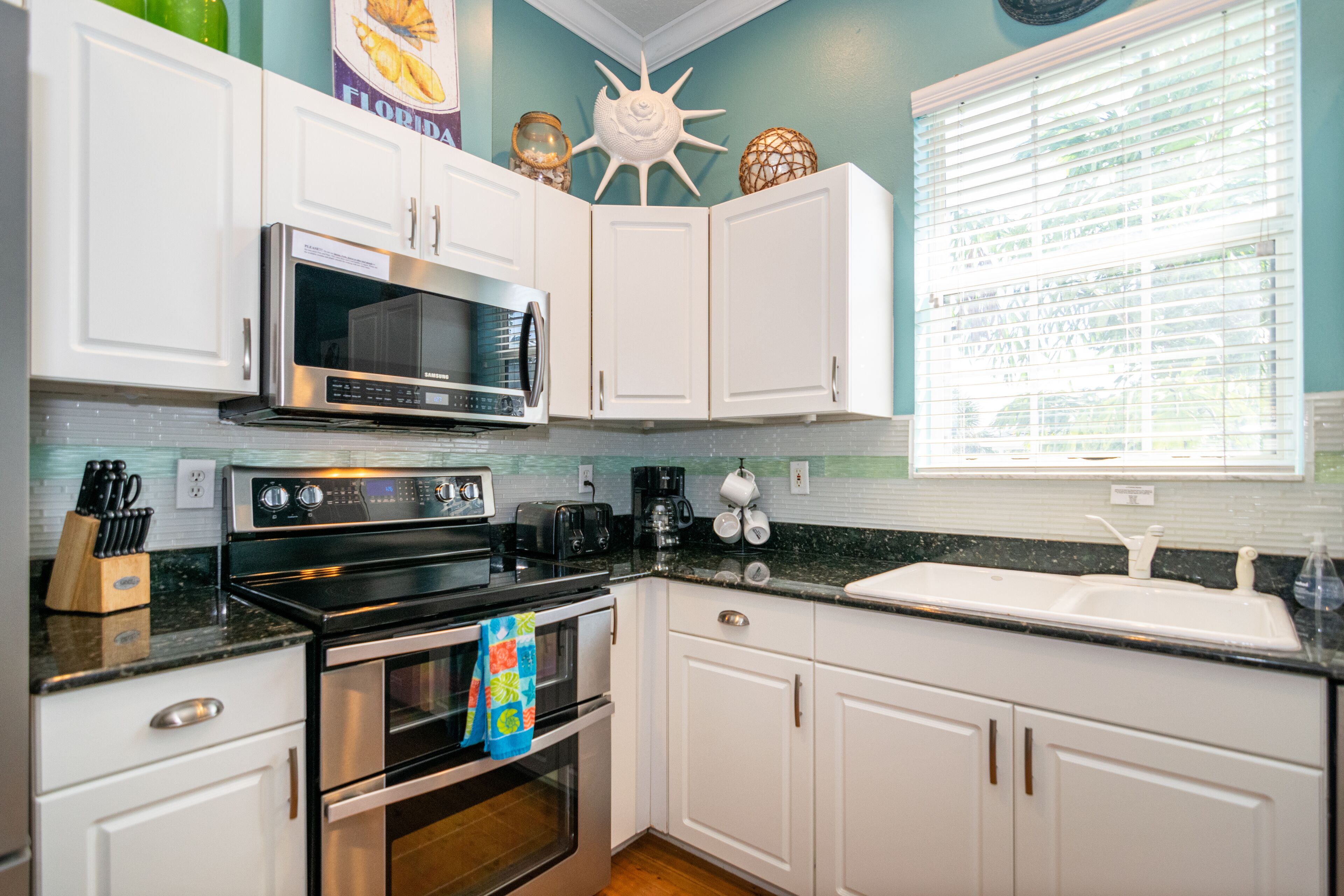 A kitchen with white cabinets, a stainless steel microwave, and a double oven.