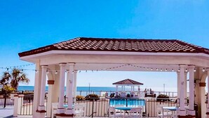 A gazebo with a tiled roof, white pillars, and a pool area with lounge chairs and tables. - Soak Up the Sun at 312-A Villa Capriani! (North Topsail Beach)
