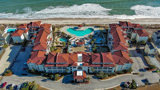 A resort with multiple buildings, a central pool, and a beach view. - Soak Up the Sun at 312-A Villa Capriani! (North Topsail Beach)