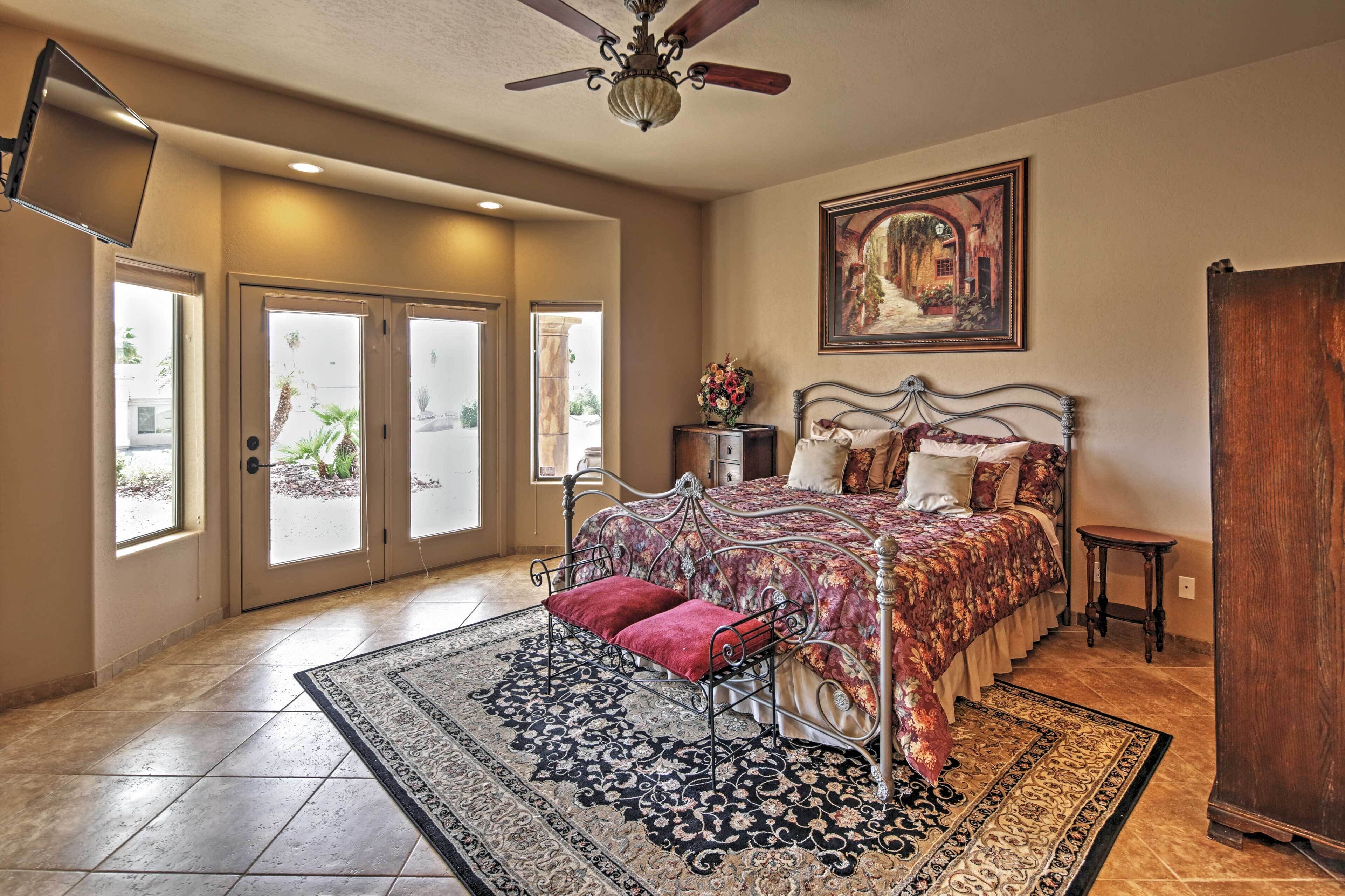 A bedroom with a bed, a ceiling fan, a painting, and a view through the door.