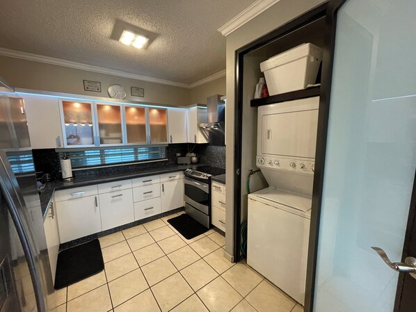 A kitchen with white cabinets, a black countertop, a built-in oven, and a dishwasher.