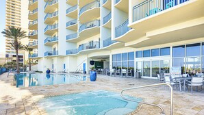 Un espace piscine d’hôtel comprenant une partie en contrebas, des chaises longues et un restaurant avec une terrasse.