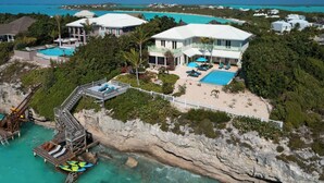 Una propiedad costera con una casa grande, piscina y un muelle con kayak.
