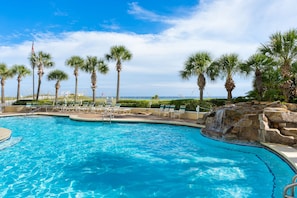 Relax by the serene pool surrounded by palm trees and a soothing waterfall.