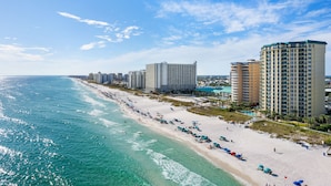 A beach with a row of high-rise hotels, clear blue skies, and turquoise ocean waters. - Beach Front, Heart of Destin, Tennis, Walk to Water Park (Destin)
