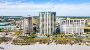 A high-rise hotel with multiple floors, a swimming pool, and a beach area with umbrellas. - Beach Front, Heart of Destin, Tennis, Walk to Water Park (Destin)
