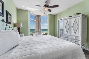 A bedroom with a large bed, a ceiling fan, a view of the ocean, and a white dresser. - Beach Front, Heart of Destin, Tennis, Walk to Water Park (Destin)