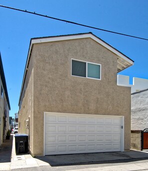 A single-story building with a garage door, a small window, and a concrete driveway.