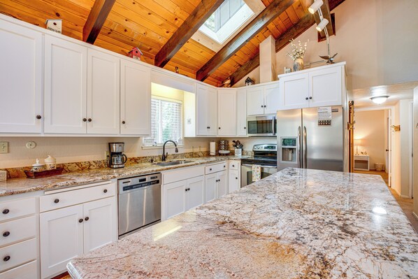 Enjoy cooking in this well-equipped kitchen with a large island countertop, dishwasher, and refrigerator.