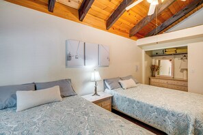 Two single beds with matching bedding, nightstands, and a large mirror create a functional and inviting space.