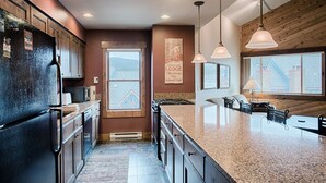A modern kitchen with granite countertops, wooden cabinets, and pendant lighting. - Ski-In Condo Featuring Vaulted Ceilings, On-Site Hot Tubs, Private Patios, Cover (Breckenridge)