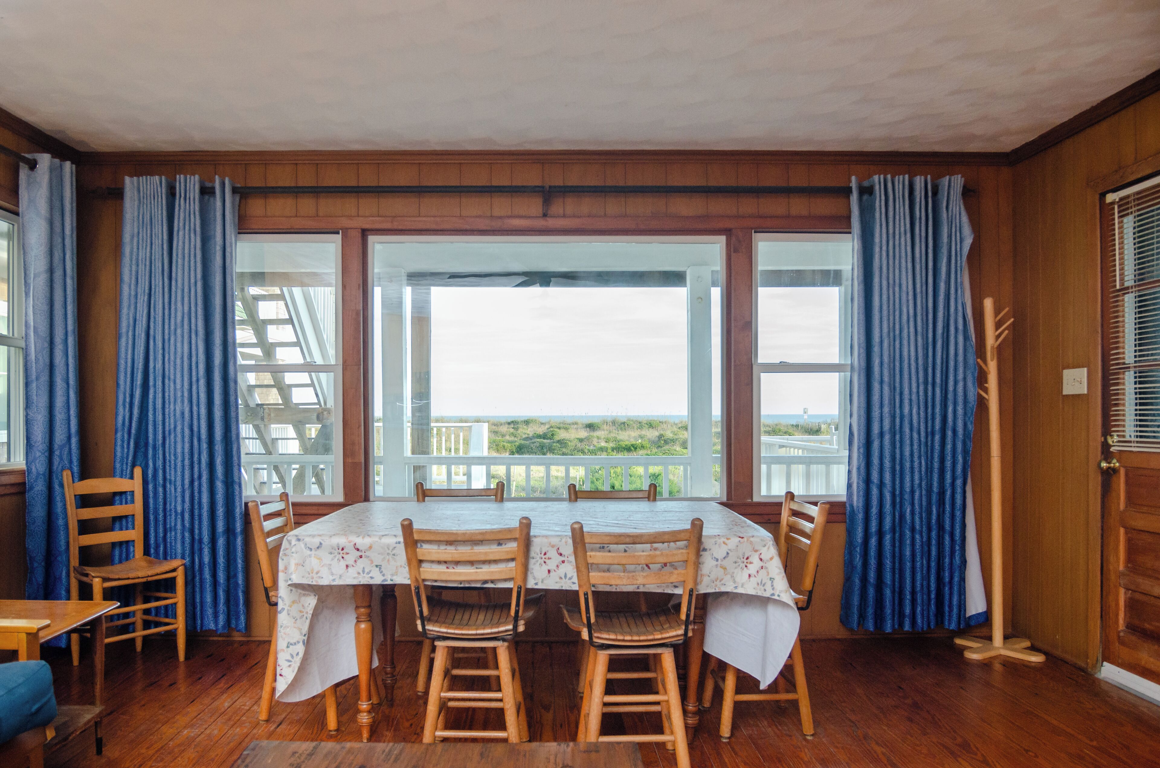 Un'area pranzo con tavolo e sedie, ampie finestre e vista sull'esterno.