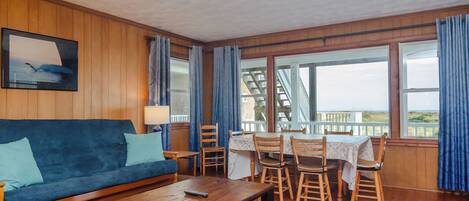 Relax in a well-appointed room with a comfortable sofa, dining area, and large windows offering a view of the outdoors.