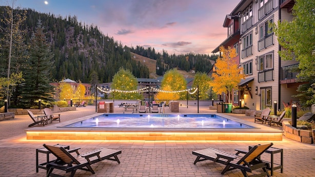 A pool area with lounge chairs, a water feature, and a view of a mountain.