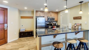 A modern kitchen with a central island, stainless steel appliances, and bar stools.