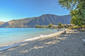 Una spiaggia con acque cristalline, una riva sabbiosa e colline sullo sfondo.