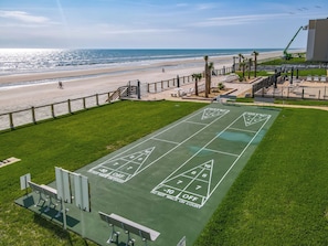 Una cancha de shuffleboard verde con vista a la playa y al océano.
