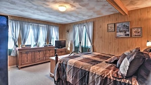 A wooden-paneled bedroom with a bed, dresser, and television.