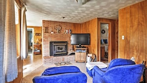 A cozy living room with a fireplace, a television, and blue armchairs.