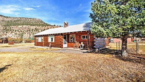 A log cabin with a front porch, a small table, and a chair.