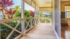 A covered outdoor area with a concrete floor, white railings, and tropical plants. - Amazing private home with AC, Pool, Garage, Hot Tub and Toys N27C (Princeville)