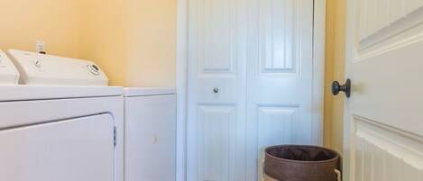 A laundry room with a washing machine, dryer, and a trash can labeled "The Laundry Room."
