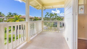 A covered porch with white railings, a concrete floor, and a view of a residential area with houses and greenery. - Amazing private home with AC, Pool, Garage, Hot Tub and Toys N27C (Princeville)
