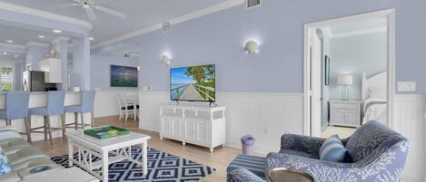 A spacious living area with a dining set, a TV, and a large mirror.