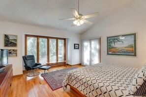 Ein Schlafzimmer mit Bett, Stuhl, Fernseher und Deckenventilator.