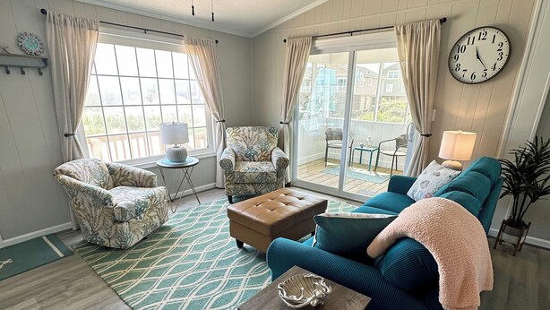 A spacious living room with a ceiling fan, a large window, and a sliding glass door leading to an outdoor patio.
