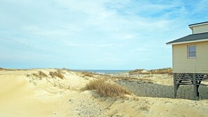 A sandy beach with dunes and a wooden structure.