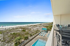 A pool area with lounge chairs and a view of the beach.