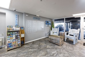 Un espace d’accueil comprenant un panneau d’affichage, un bureau, une chaise et donnant sur le parking.