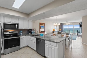 A modern kitchen with built-in appliances, a central island, and a view of the ocean.